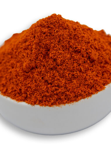 A white bowl filled with paprika ground, showcasing their smooth texture and deep orange color.