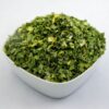 A white bowl filled with dried chives, showcasing their fine, green threads and vibrant color.