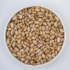 A close-up of dry pinto beans in a white bowl, showcasing their natural speckled texture.